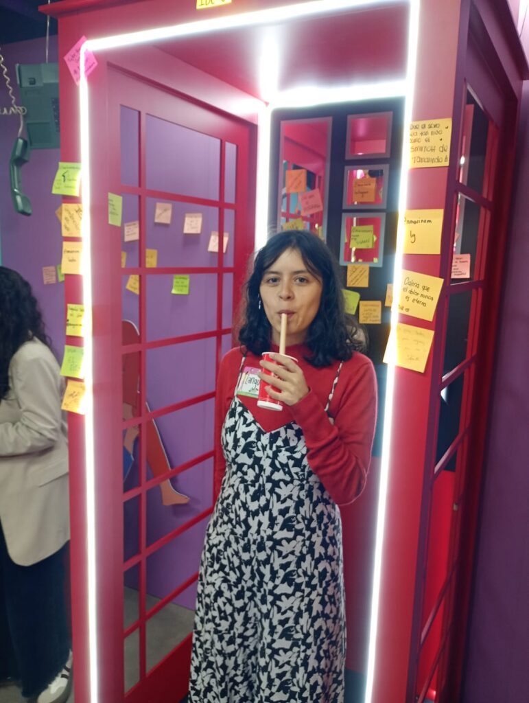Colombian singer-songwriter Zarigüeya at a promotional event for Festival Estéreo Picnic 2026. She is in a red phone box drinking through a straw.